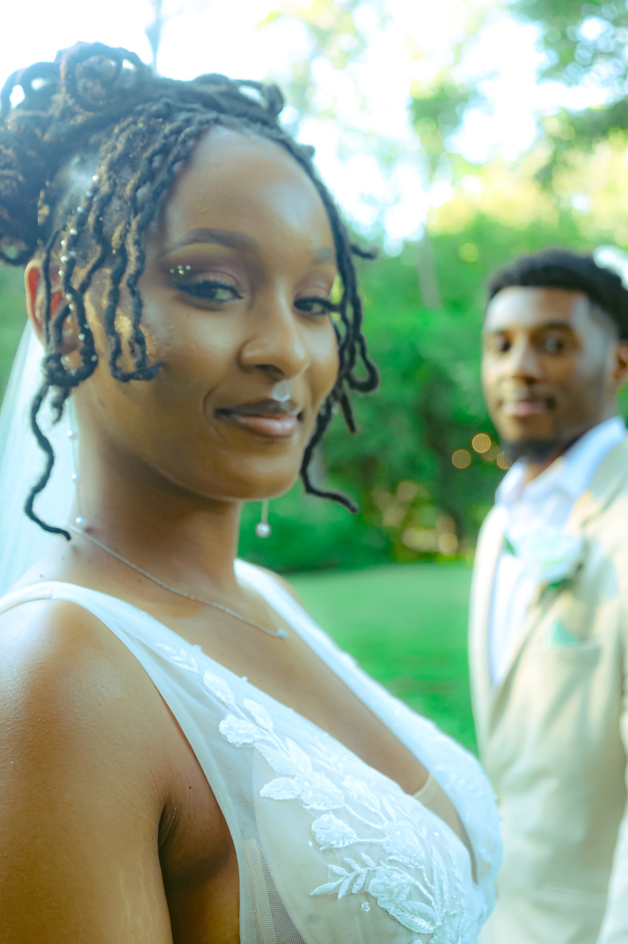 Close-up bridal portrait with groom in background